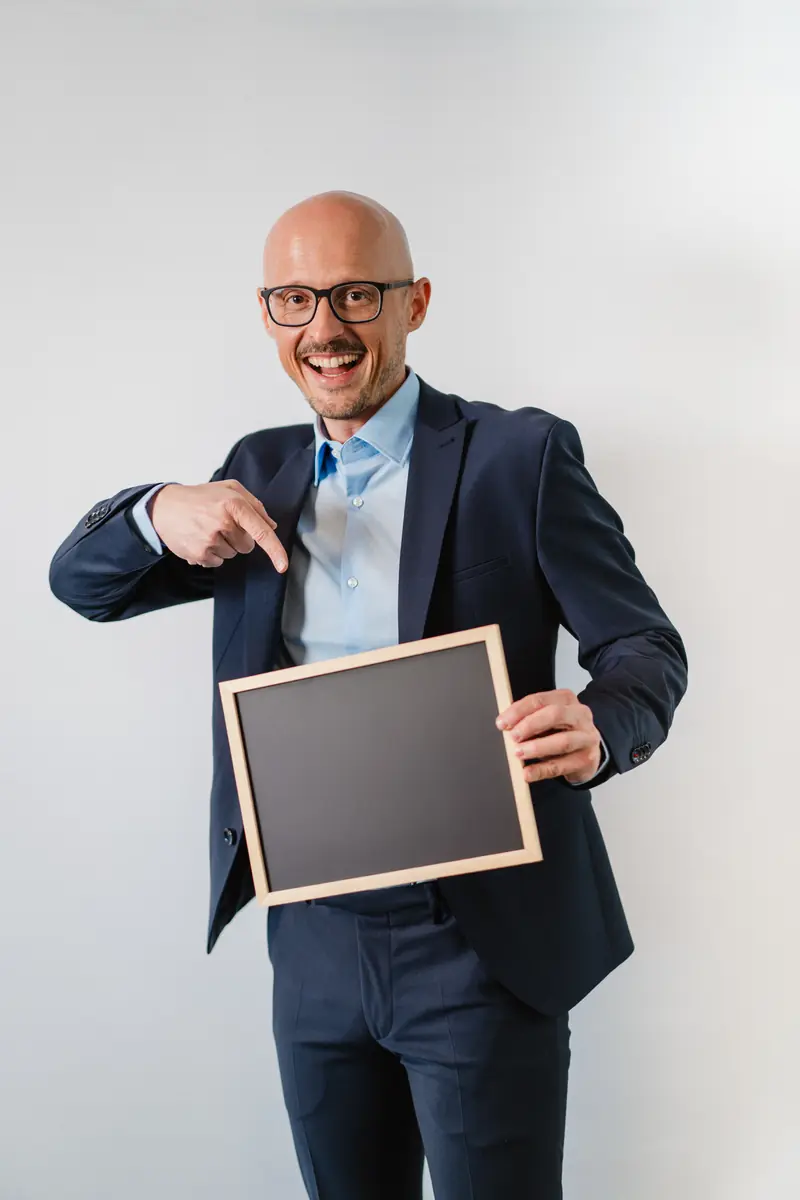 Daniel Pfingstl zeigt auf eine leere Tafel, Platz für deinen besseren Job